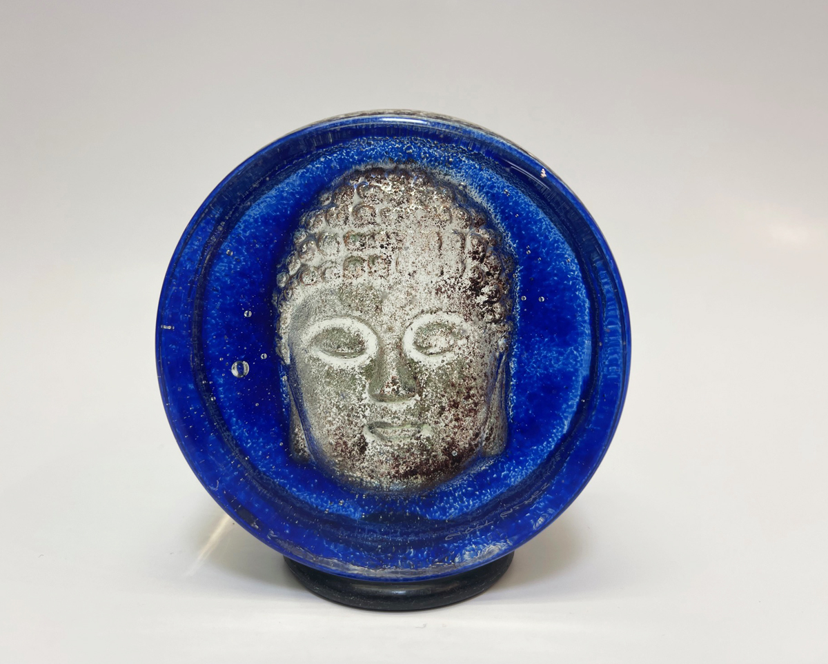 Solid glass handmade paperweight in blue with Buddha face.